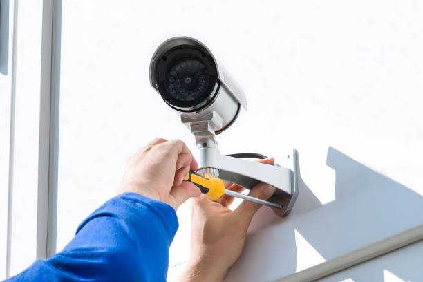 Technician Fixing Camera On Wall With Screwdriver Technician Fixing Camera On Wall With Screwdriver