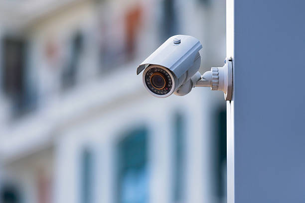 An infrared security camera on a building facade above a city street. An infrared security camera on a building facade above a city street.