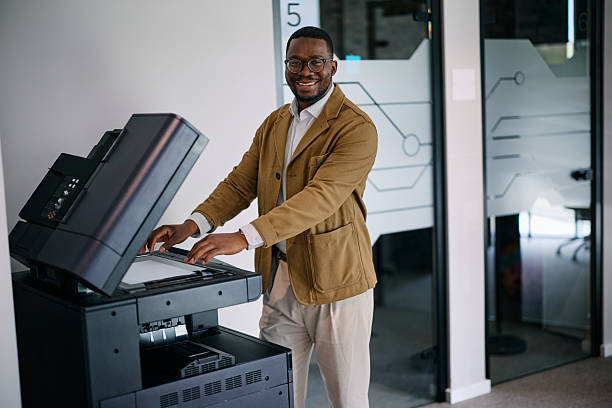 p6 Cheerful African American manager using a multifunctional printer in a modern office, efficiently handling paperwork and administrative tasks with a positive attitude